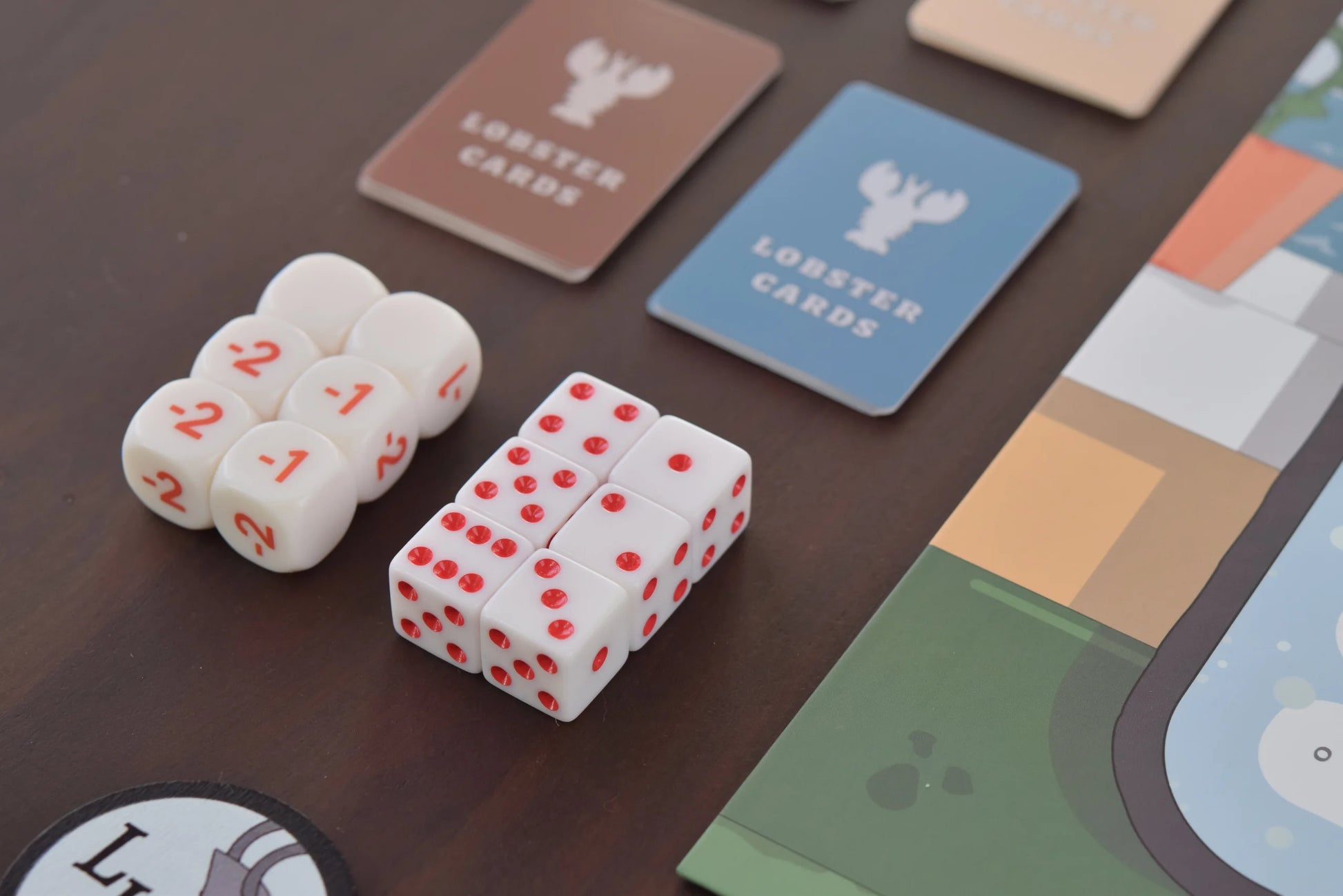 Lobster Pot - White six-sided dice with red dots and lobster claw illustrations on a dark brown surface alongside lobster-themed cards.