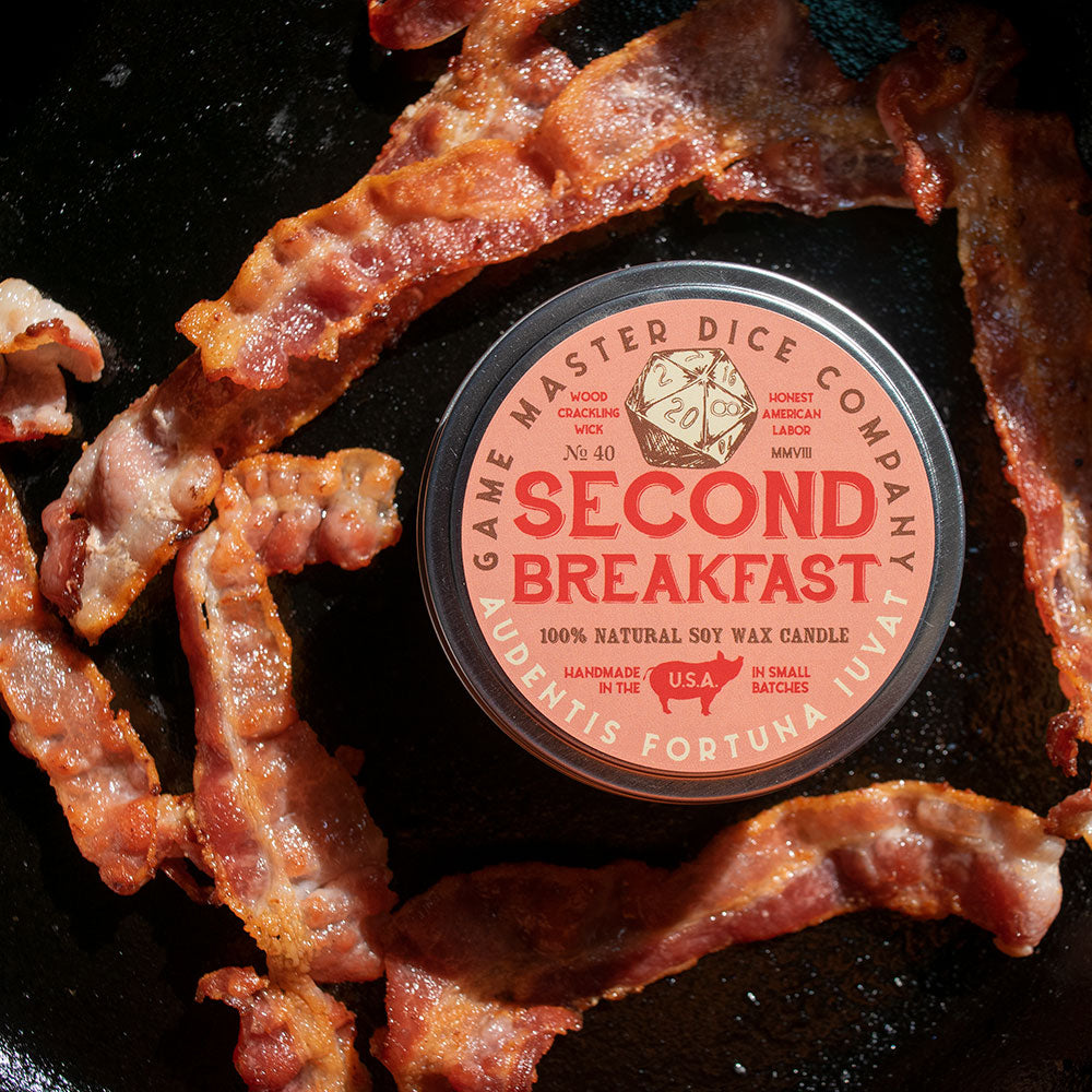 Second Breakfast Candle - Round candle tin with beige and red label reading "Second Breakfast," surrounded by crispy cooked bacon strips against a.