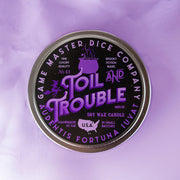 Toil and Trouble Candle - Round metal tin candle with black lid featuring purple and white gothic-style text "Toil and Trouble" and witch-themed.