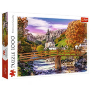 Puzzle: Autumn Bavaria 1000pc - 1000-piece puzzle box featuring autumn landscape in Bavaria with colorful trees, wooden bridge, church, and mountains.