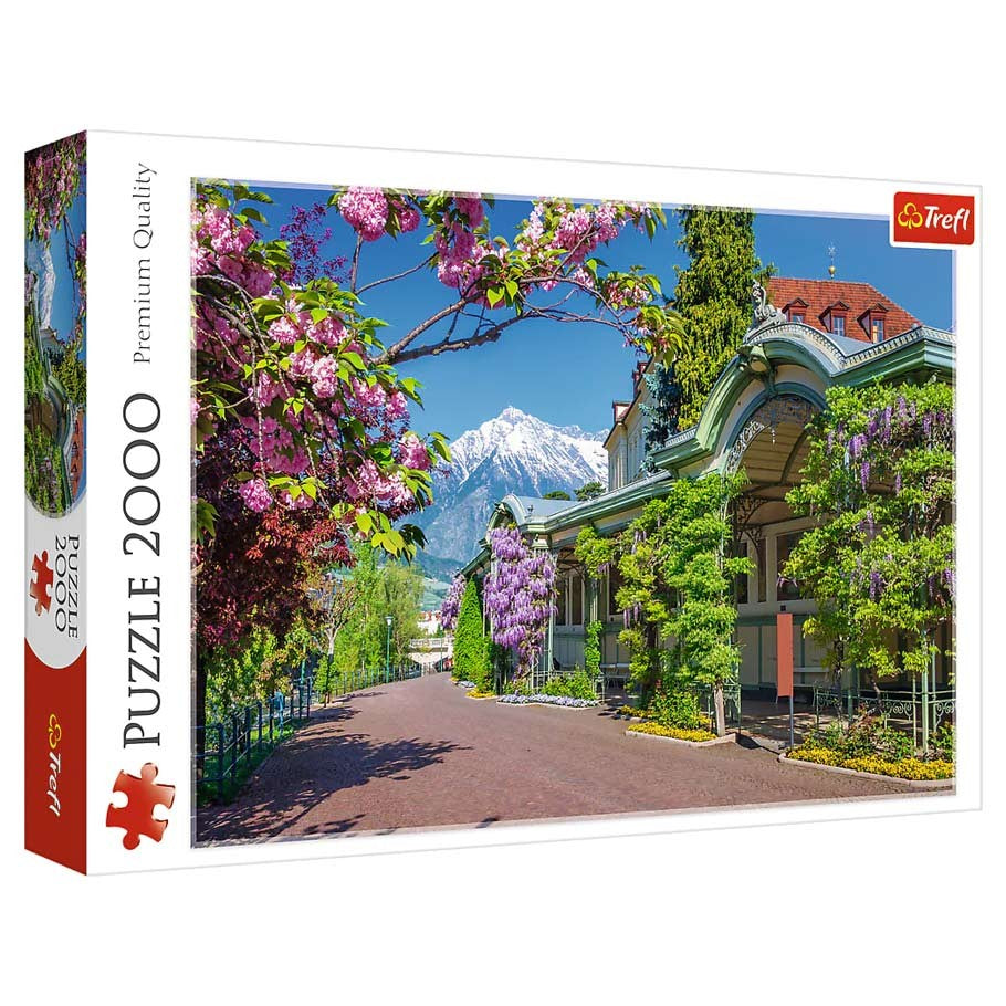 Merano, Italy 2000 Piece Puzzle - 2000-piece puzzle box featuring vibrant Merano, Italy scene with flowering trees, mountain backdrop, and historic buildings.