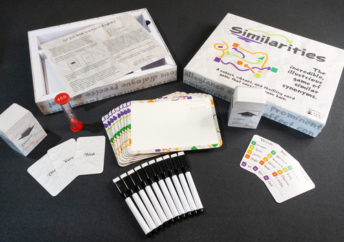 Similarities - Party game set titled Similarities with dry erase markers, cards, timer, score sheets, and game instructions arranged on a.