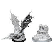 Dungeons & Dragons: Nolzur's Marvelous Minis: White Dragon Wyrmling - Unpainted white dragon wyrmling miniature with outstretched wings and sharp claws on a black base, next to a rocky terrain.