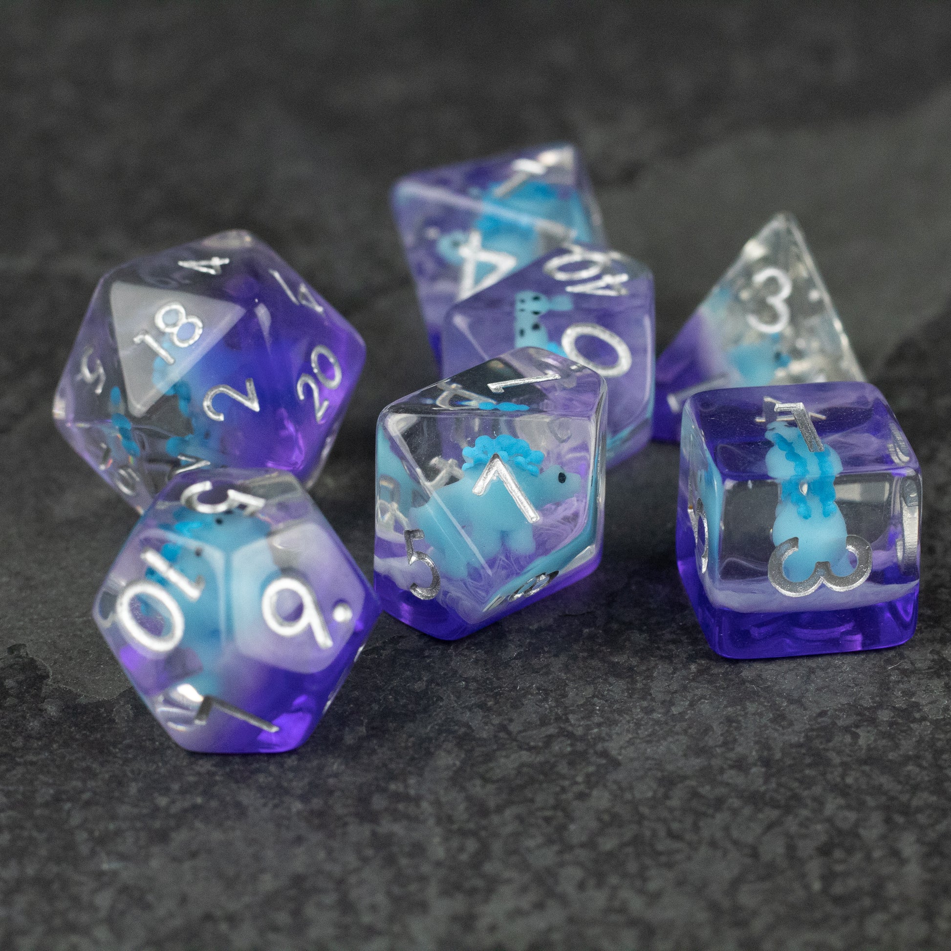 Blue Stegosaurus Dice Set - Set of translucent blue and purple polyhedral dice featuring numbers and a stegosaurus figure inside one die.