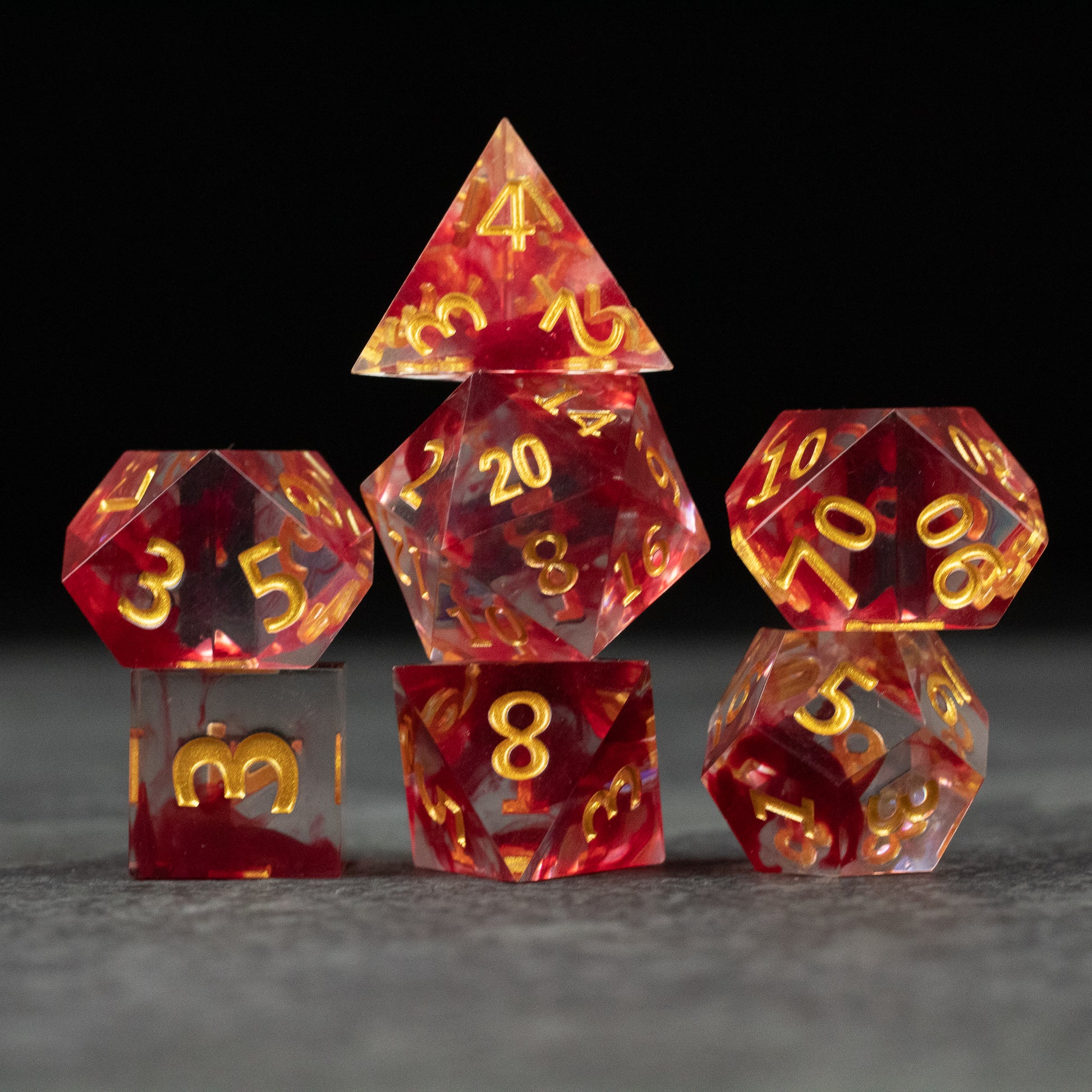 Blood Pact Dice Set - Red translucent polyhedral dice set with gold numbers, sharp edges, includes d4, d6, d8, d10, d12, and d20 shapes.