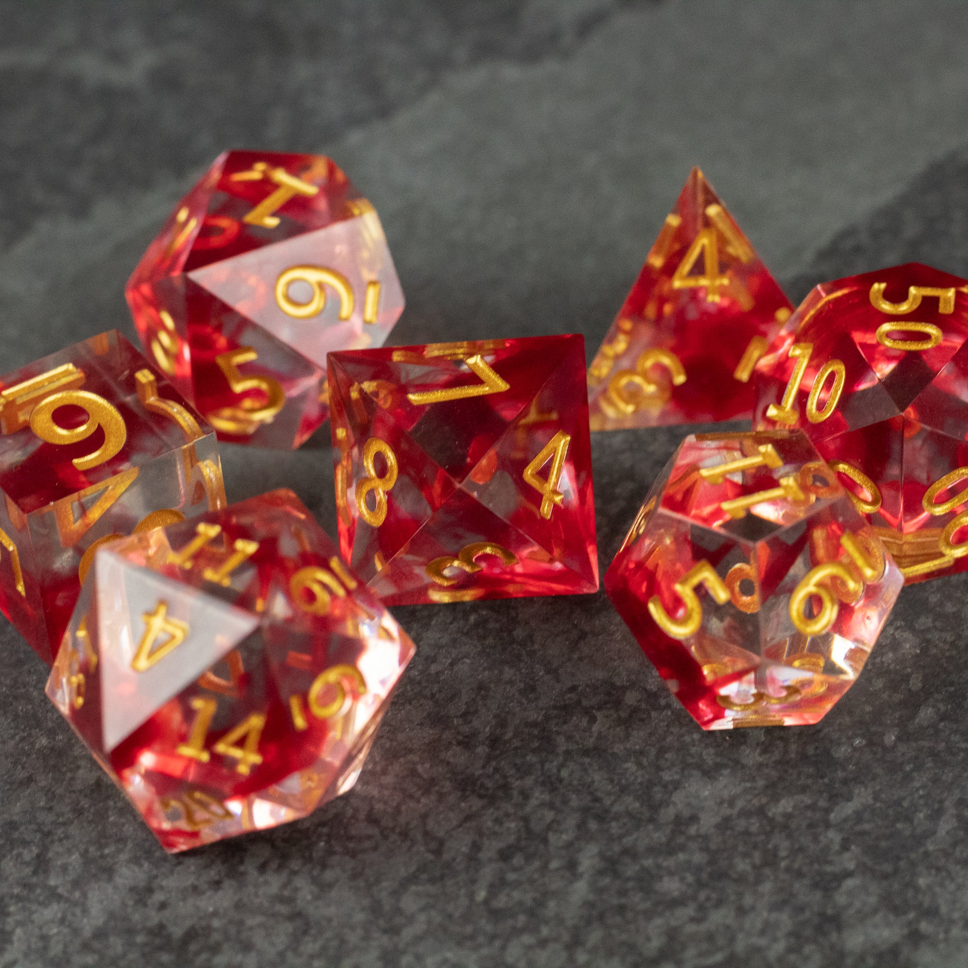 Blood Pact Dice Set - Translucent red seven-piece dice set with sharp edges and gold numbering.