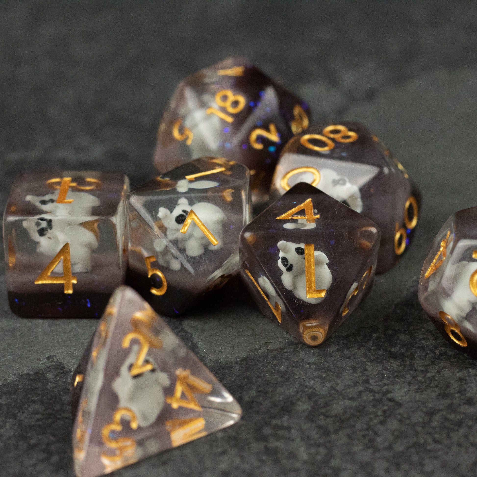 Elephant Dice Set - Set of translucent purple polyhedral dice with gold numbers and small white elephant inclusions inside.