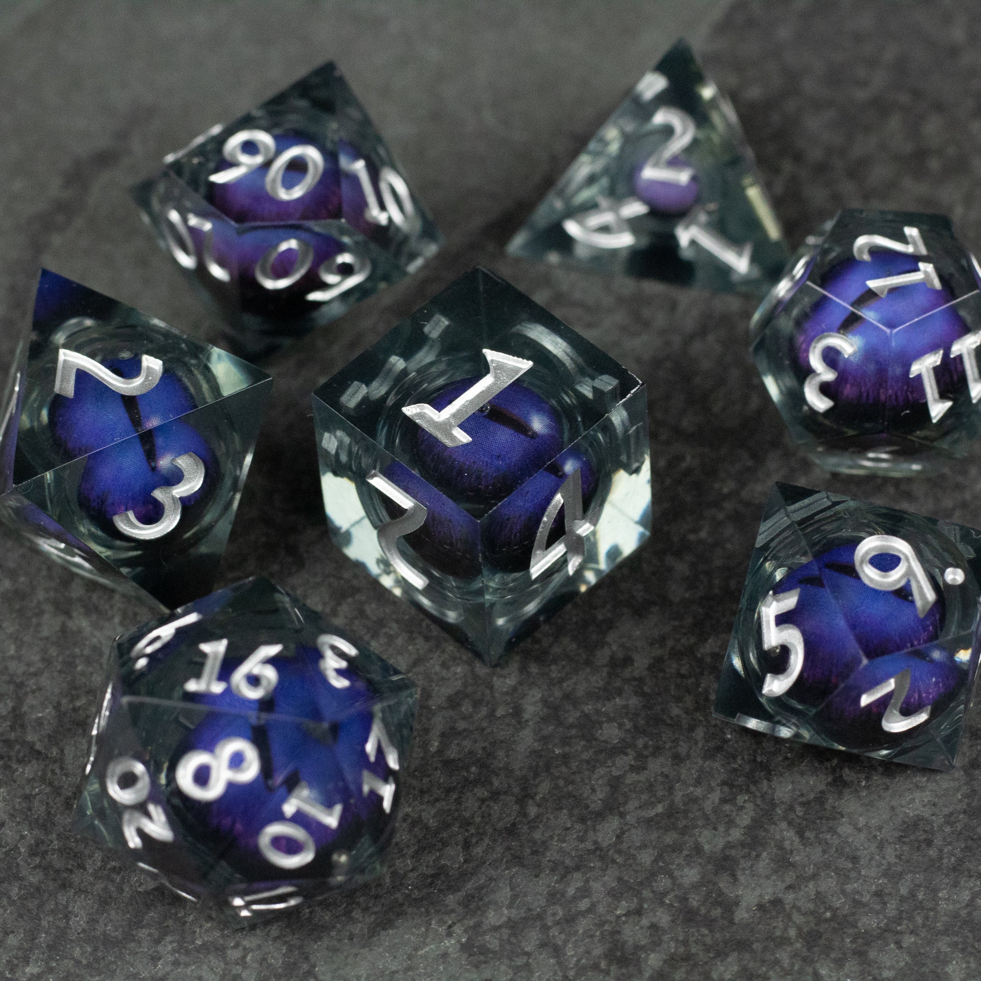 Purple Beholder's Eye Dice Set - Set of seven sharp-edged dice with purple liquid core and white numbers on transparent black outer shell.