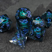Blue Beholder's Eye Dice Set - Sharp-edged blue polyhedral dice set with glowing green liquid core and translucent faces.
