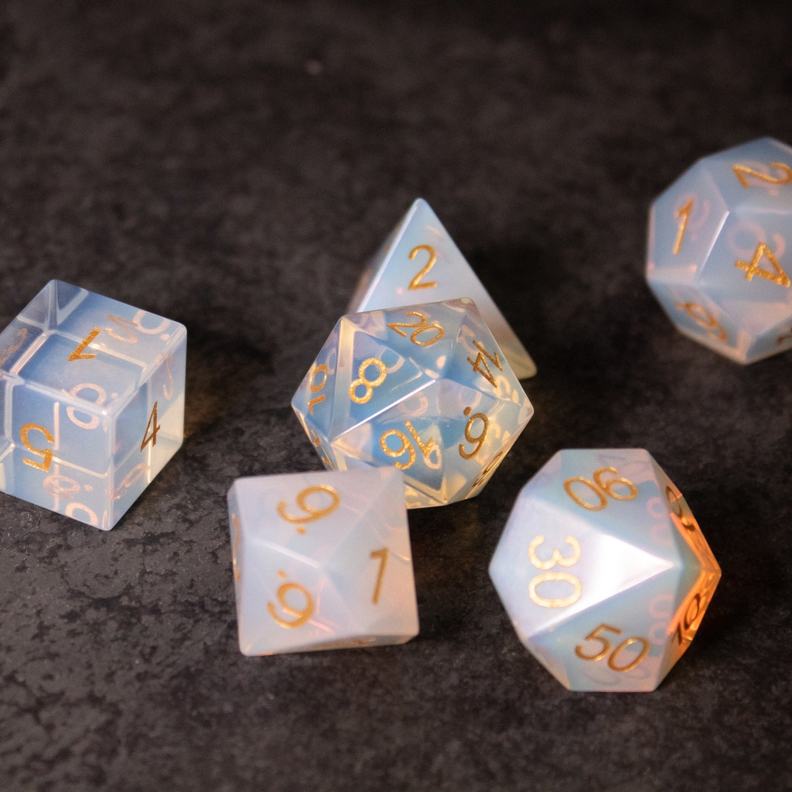 Opalite Gemstone Dice Set - Translucent opalite gemstone dice set with gold numbering, including d4, d6, d8, d10, d12, and d20 shapes.