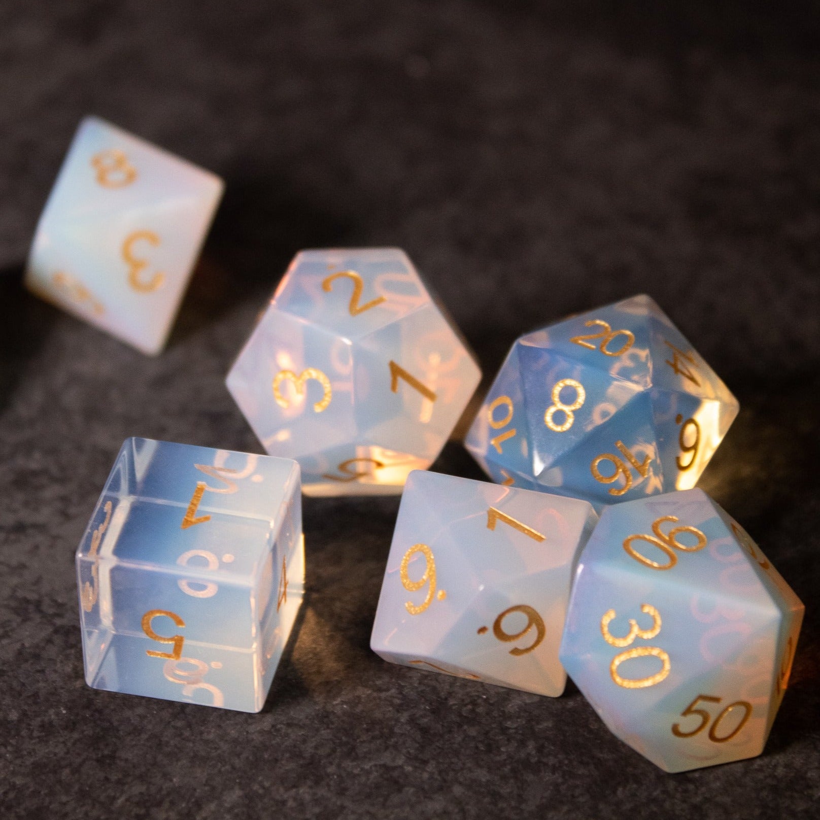 Opalite Gemstone Dice Set - Translucent opalite gemstone dice set with gold numbers, including d4, d6, d8, d10, d12, and d20 shapes.