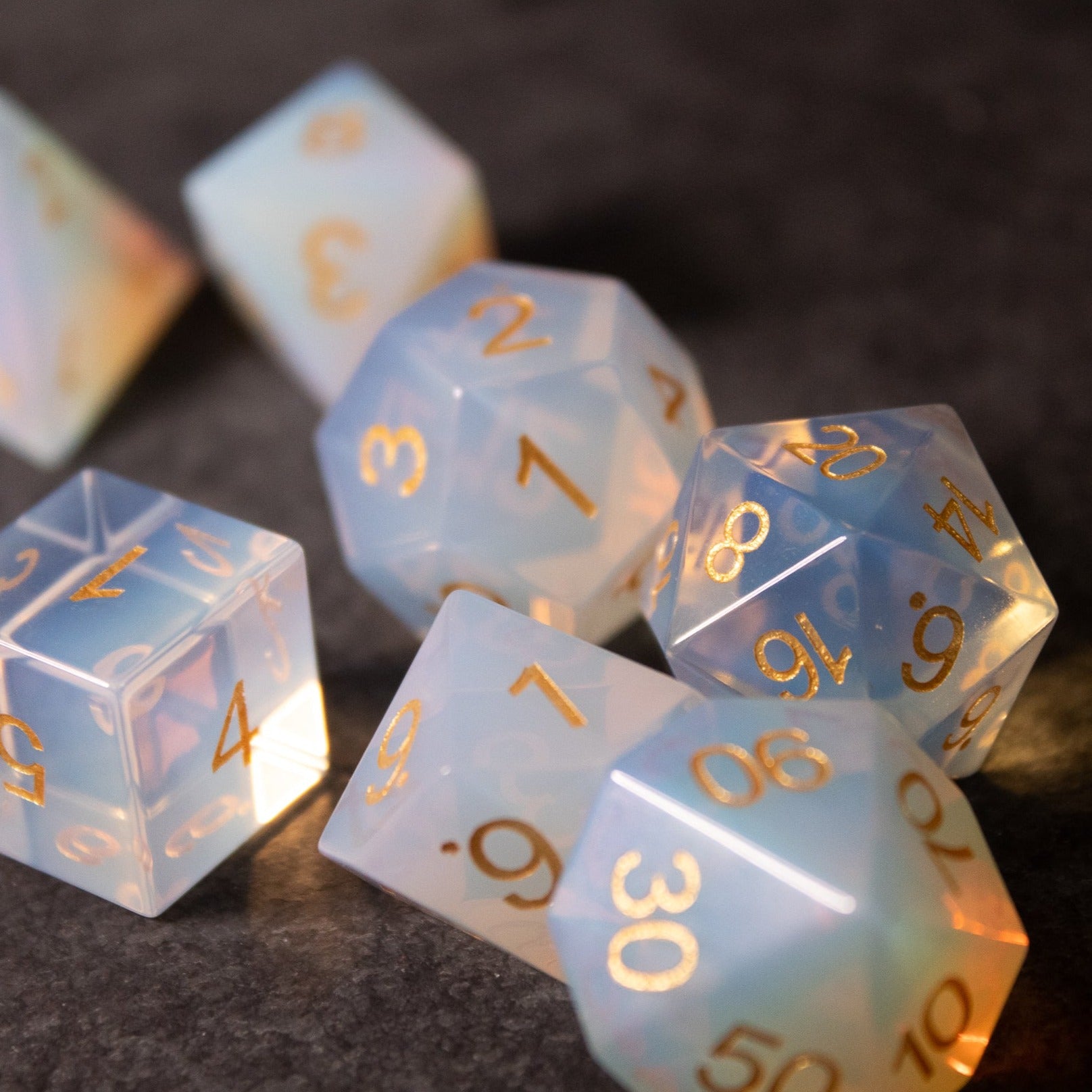 Opalite Gemstone Dice Set - Translucent opalite gemstone dice set with gold etched numbers, featuring a mix of polyhedral shapes including d20, d12,.