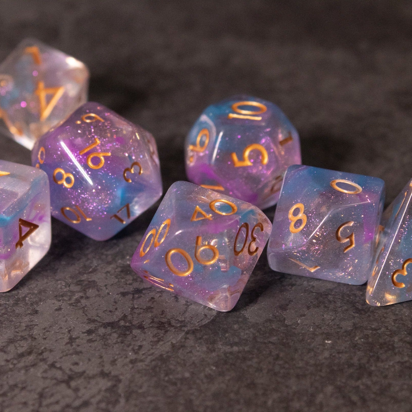 Cotton Candy Dice Set - Set of seven translucent dice in pastel pink and blue with gold numbers, featuring various polyhedral shapes.