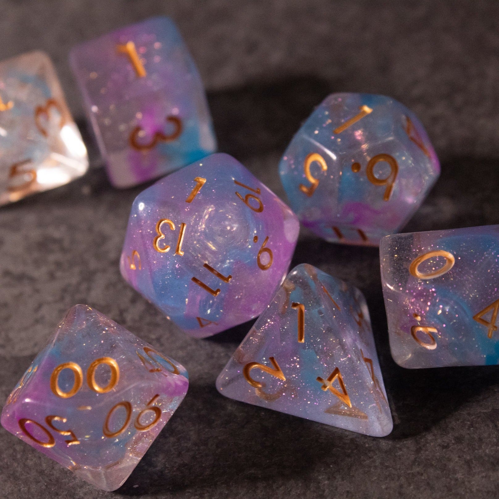 Cotton Candy Dice Set - Translucent blue and pink polyhedral dice set with gold numbering and shimmering glitter inside.