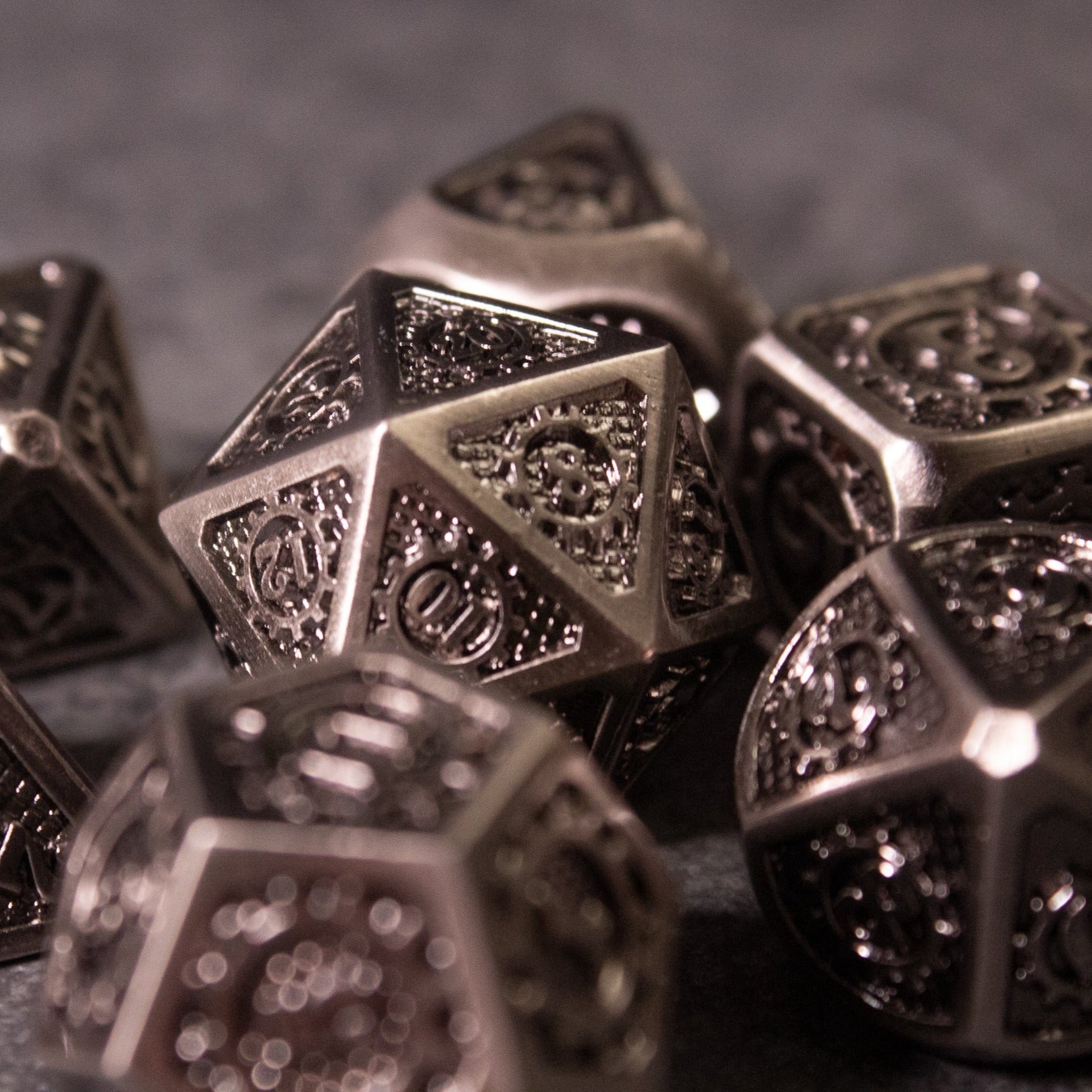 Metal Gear Dice Set - Set of dark metal polyhedral dice with intricate gear and cog engravings on each face.