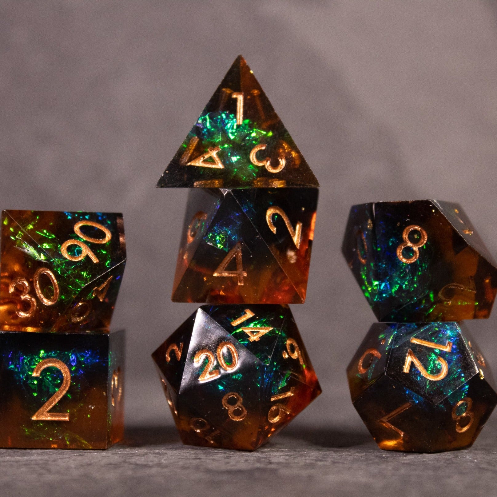 Whiskeyjack Dice Set - Whiskeyjack sharp edge dice set with smoky amber and green swirls, gold numbering, seven polyhedral dice.