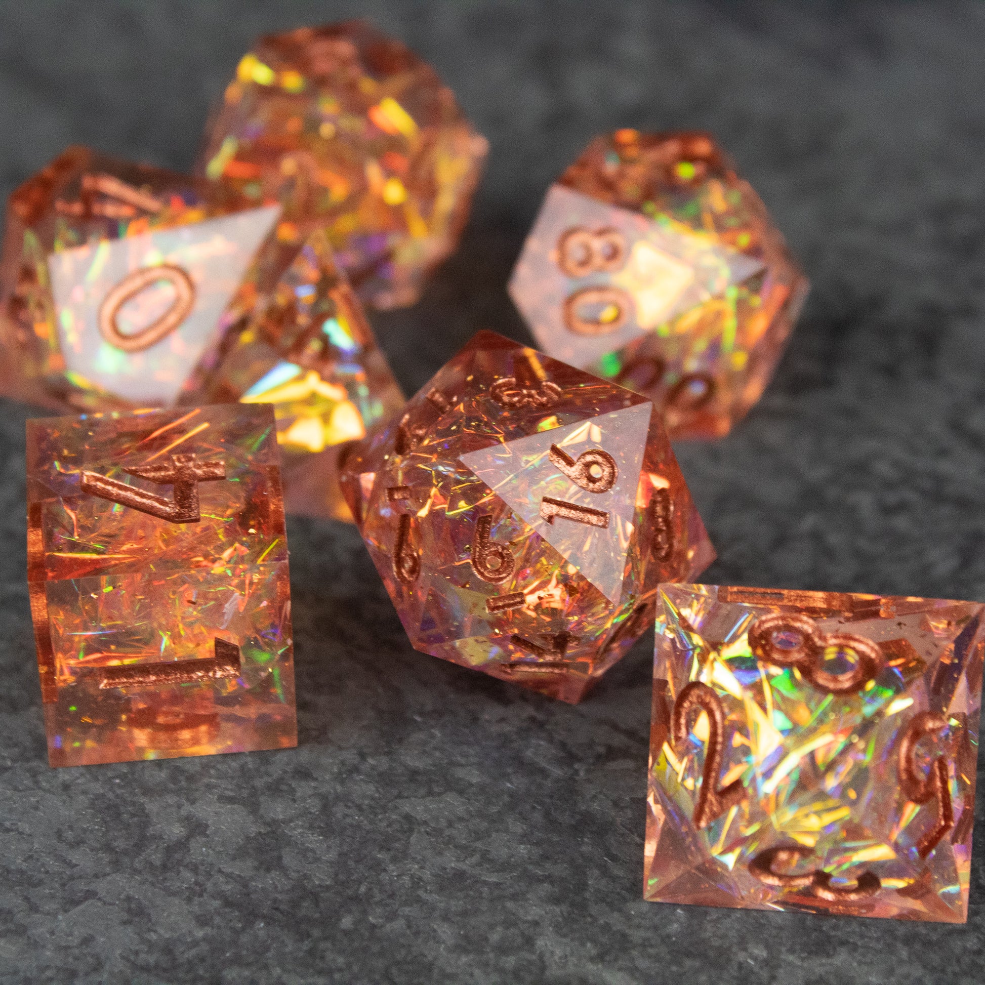 Sacred Flame Dice Set - Set of seven translucent orange sharp-edged polyhedral dice with fiery iridescent inclusions on dark surface.