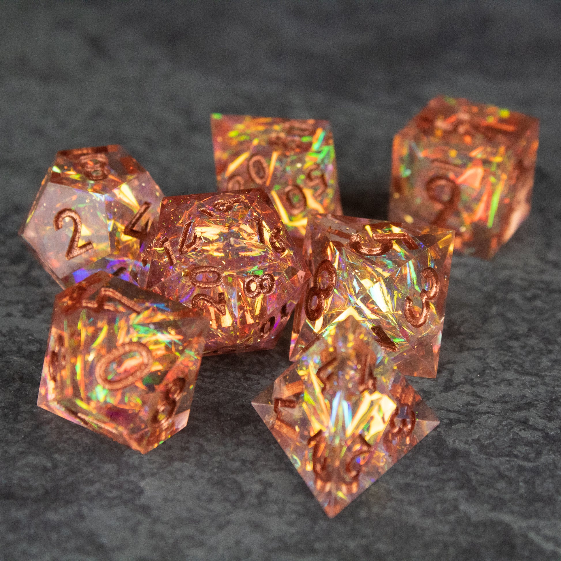 Sacred Flame Dice Set - Seven translucent orange polyhedral dice with sharp edges and gold numbering on a dark textured surface.