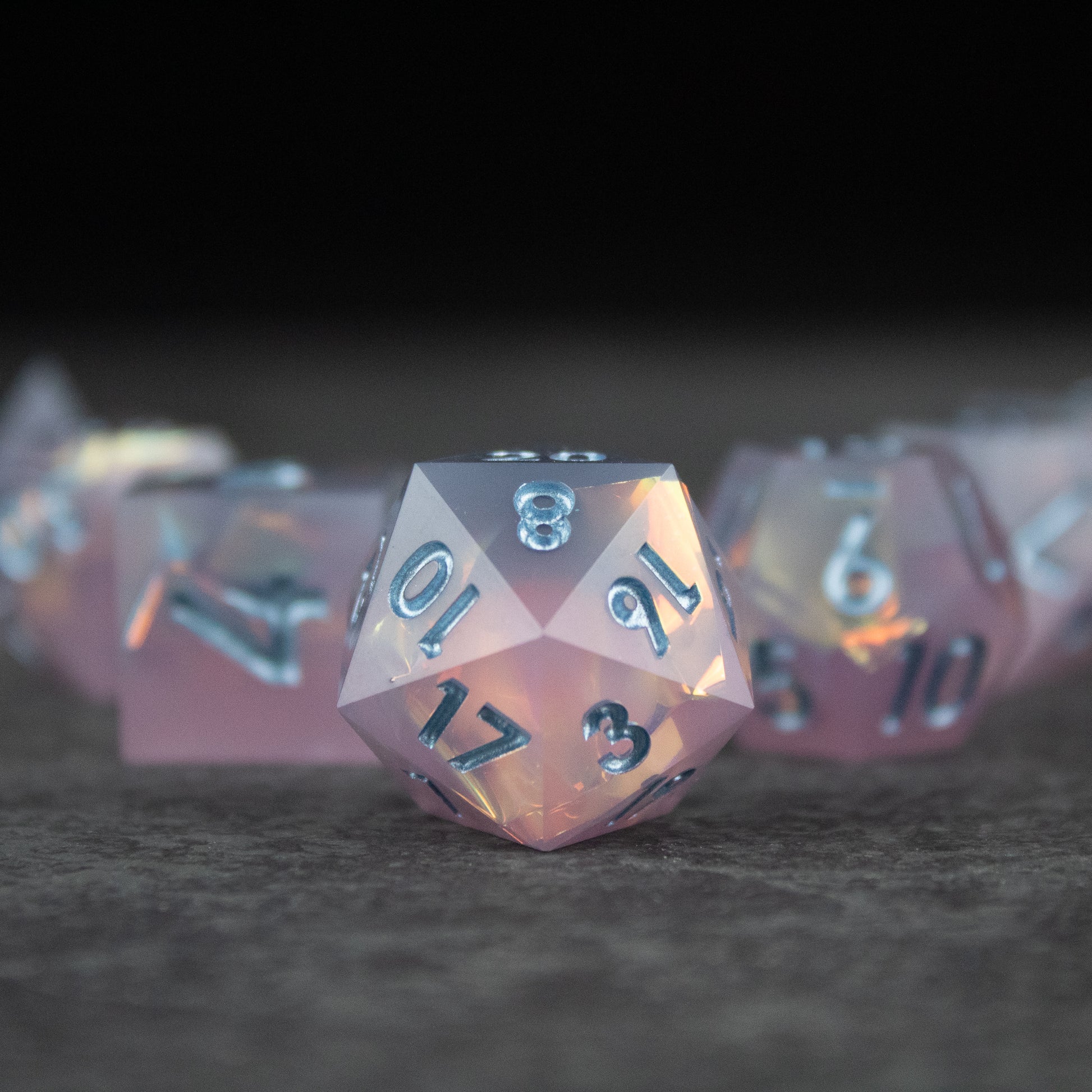 Moonshard Dice Set - Translucent pink sharp-edged 20-sided dice with silver numbers and glossy finish.