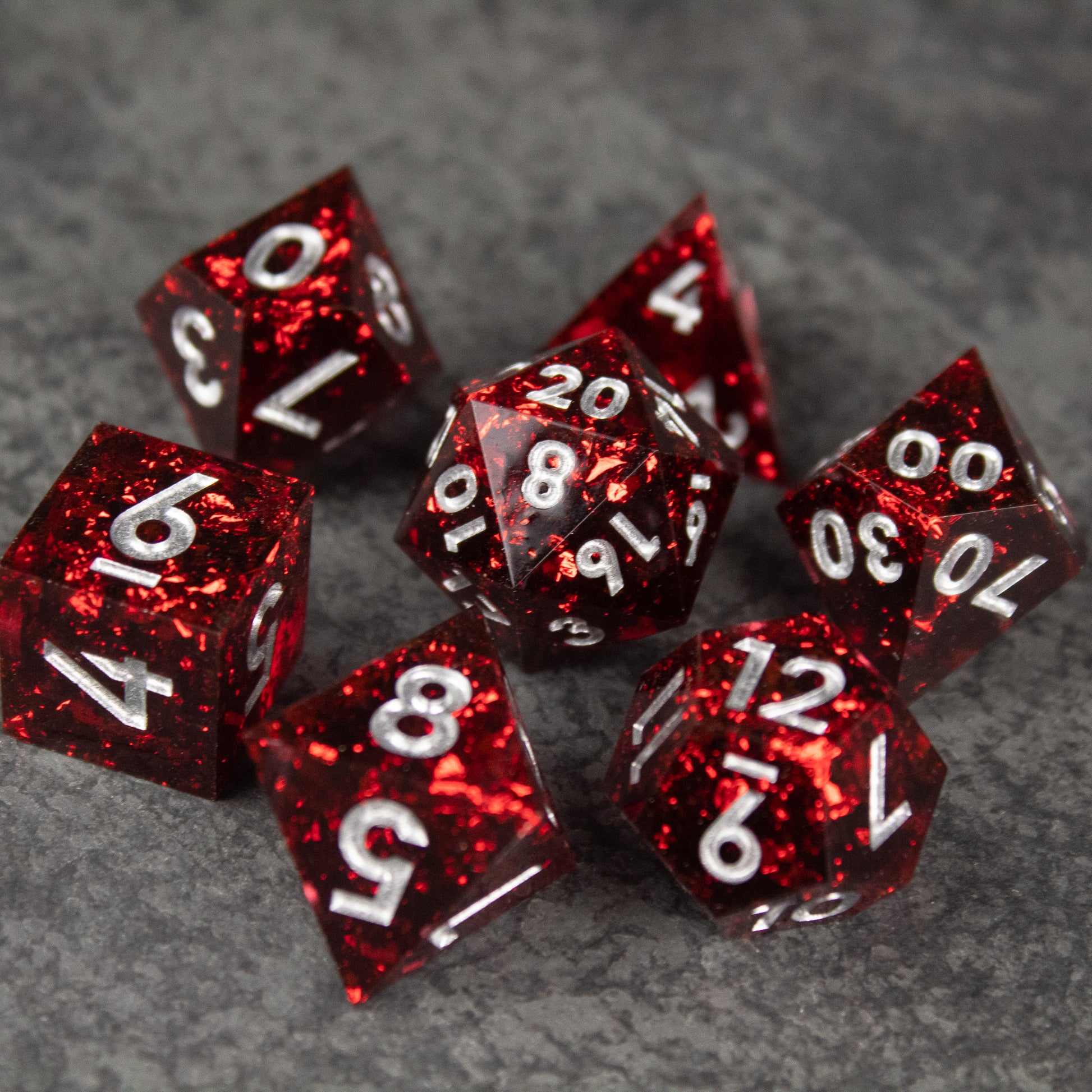 Inferno Dice Set - Red translucent polyhedral dice set with sharp edges and white numbers on gray background.