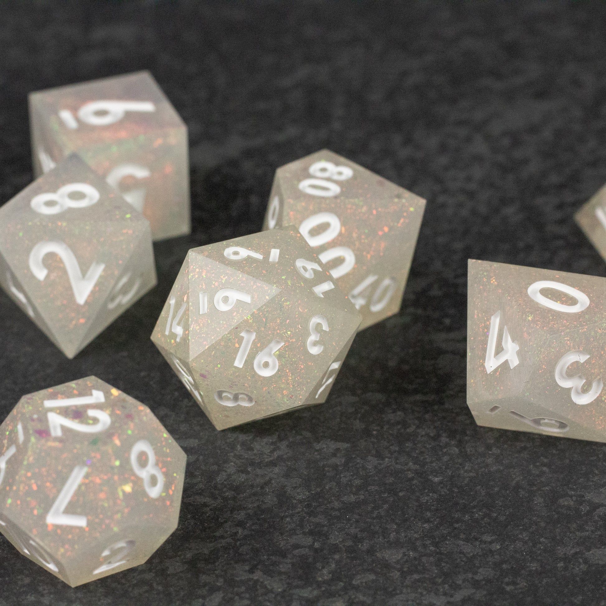 Snowfield Dice Set - Translucent white sharp-edged polyhedral dice set with silver numbers on black textured surface.
