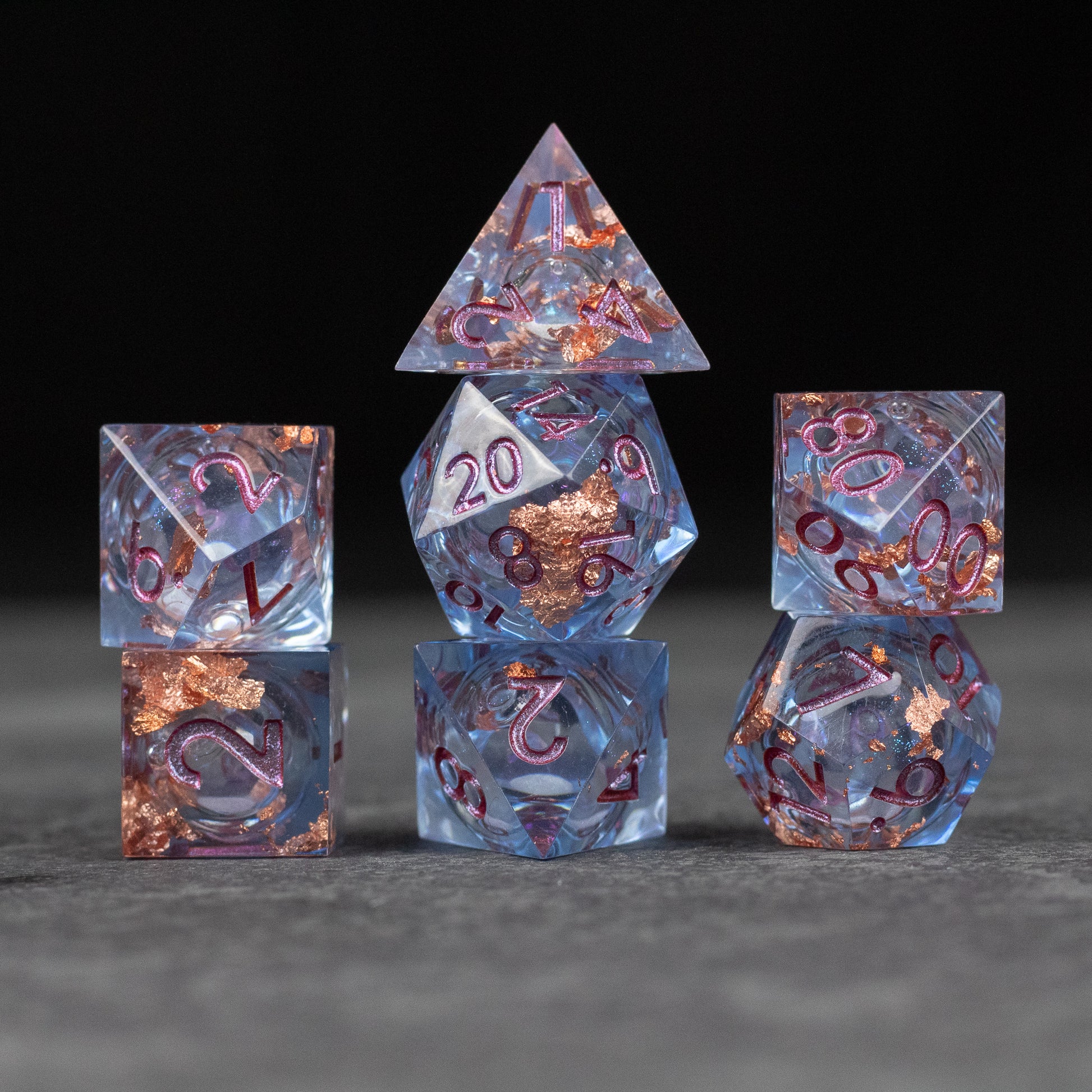 Temporal Rift Liquid Core Dice Set - Set of seven translucent blue polyhedral dice with sharp edges, featuring liquid core with copper flakes and rose gold.
