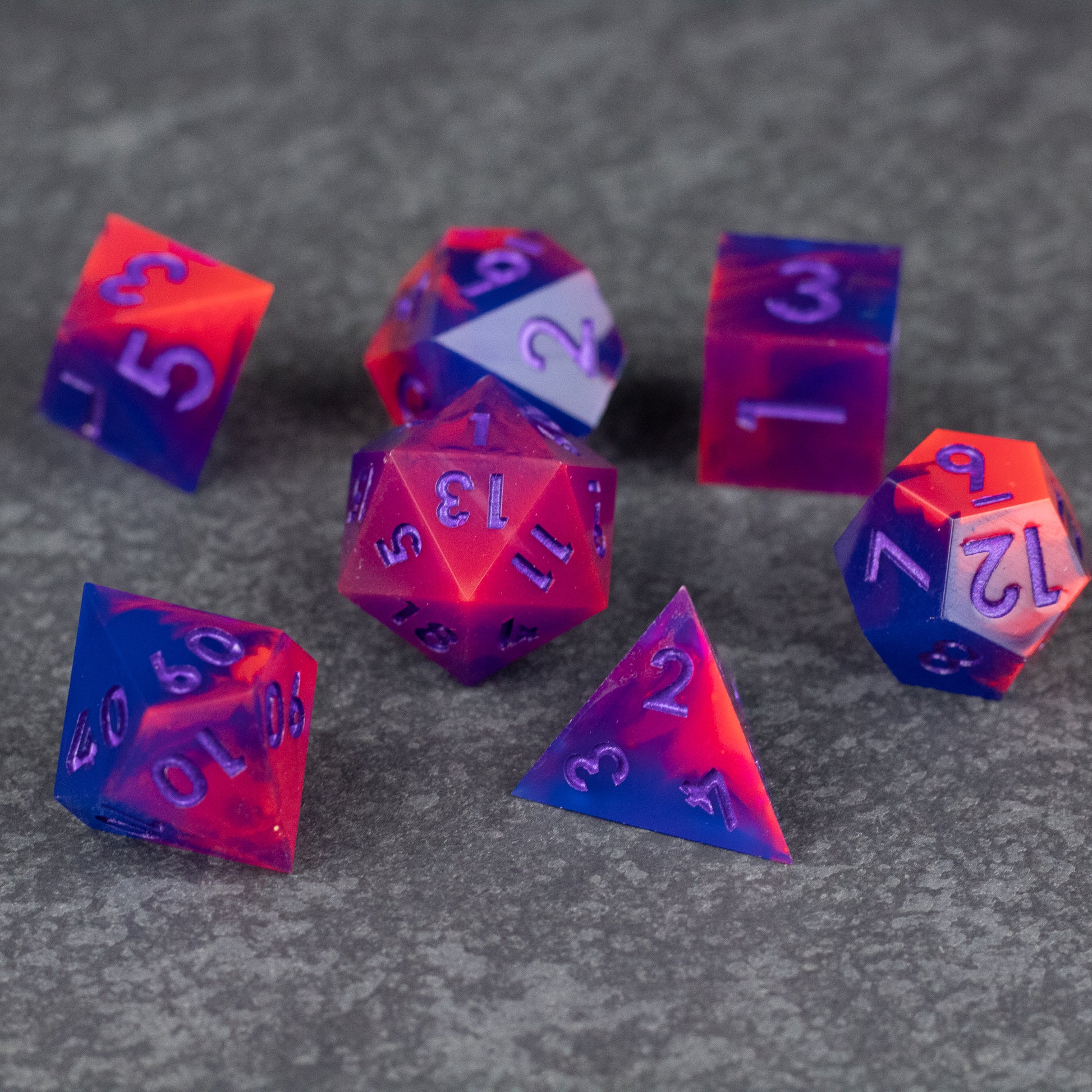 Outrun Dice Set - Set of seven neon orange and purple sharp-edged polyhedral dice with white numbers on a gray surface.
