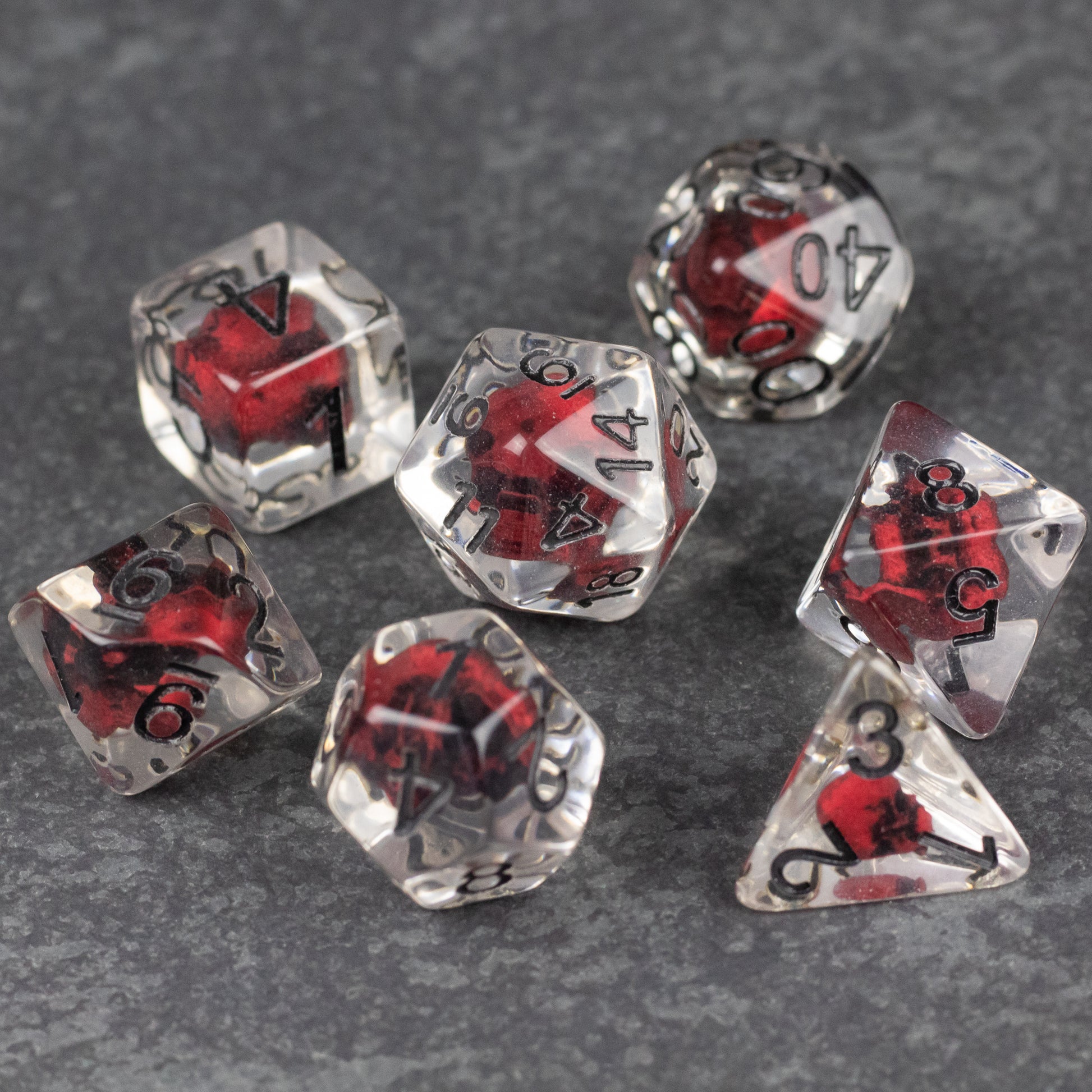 Red Skull Dice Set - Transparent polyhedral dice set with red skulls inside and black numbering.