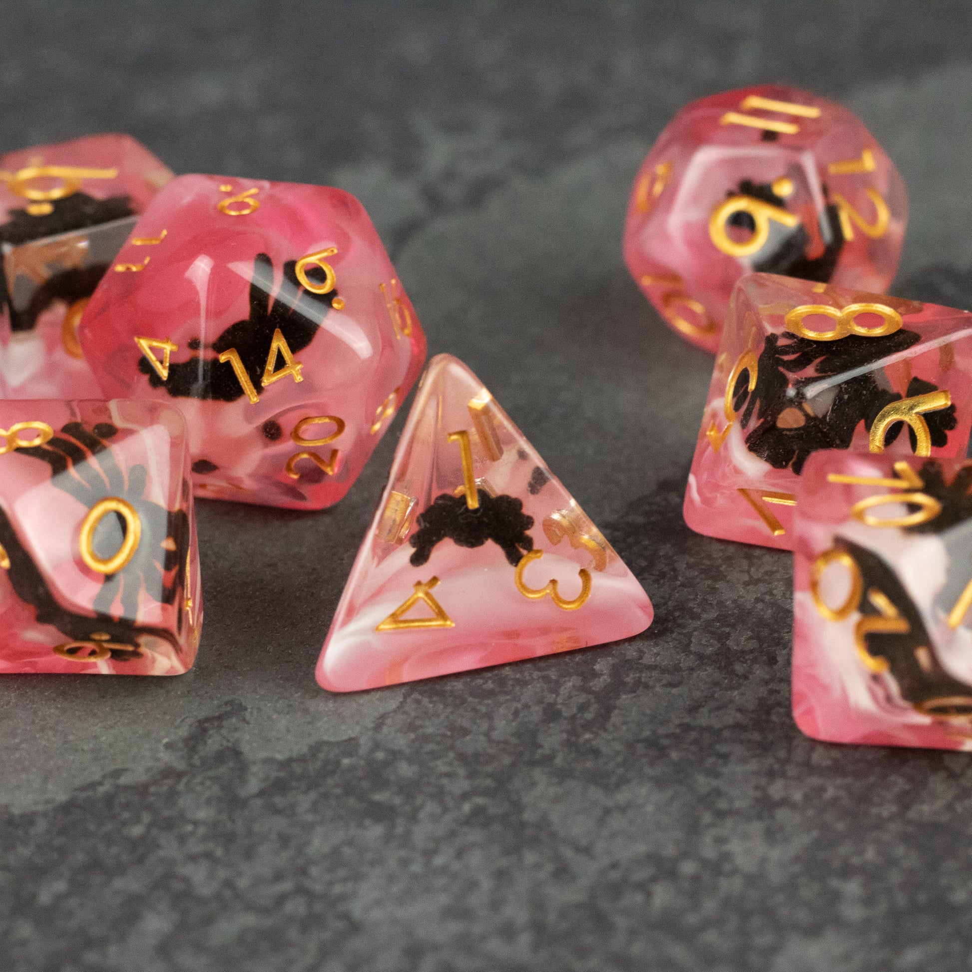 Black Spider Dice Set - Red - Red translucent polyhedral dice set with black spider designs and gold numbering on a dark surface.