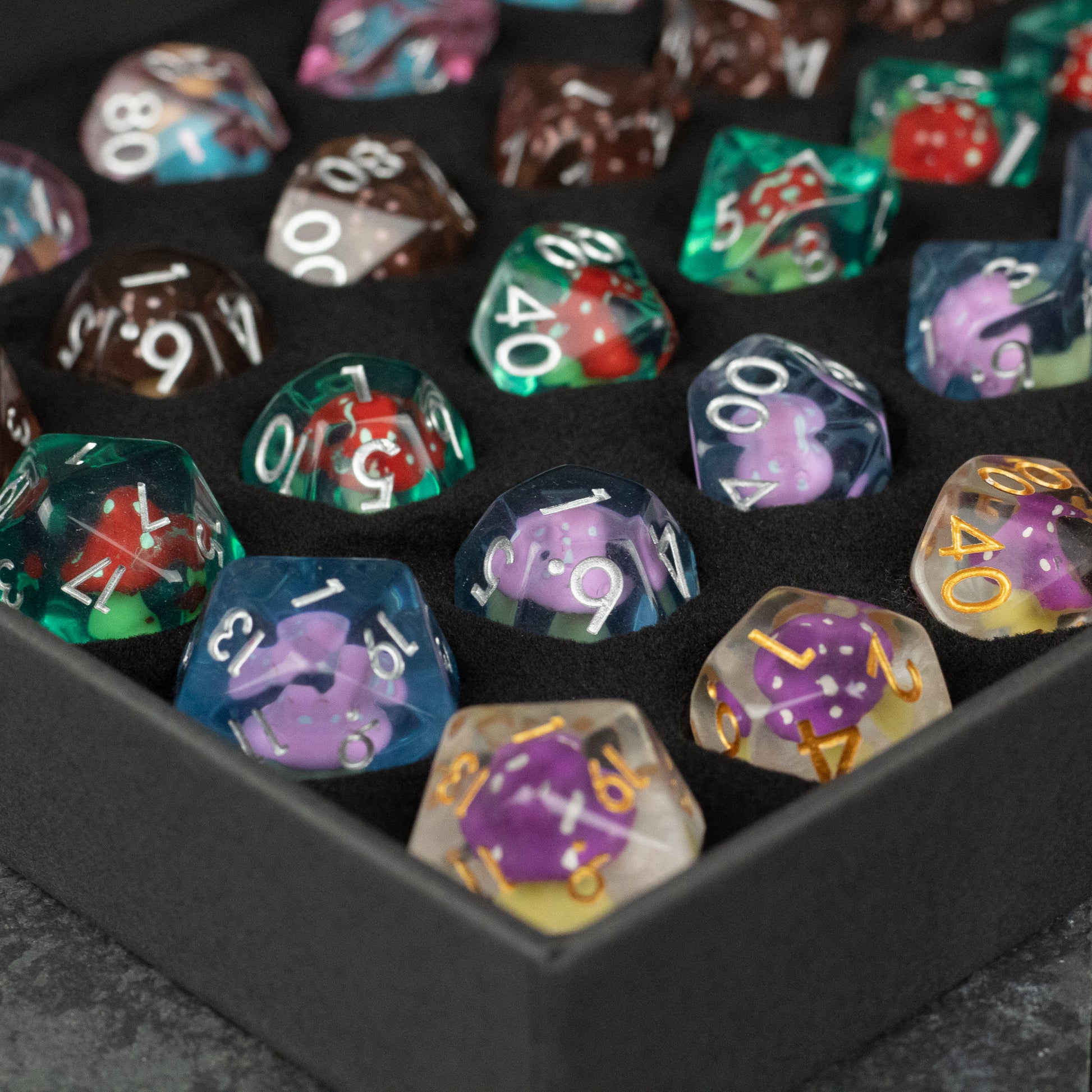 Mushroom Dice Set Gift Box - Transparent polyhedral dice set with colorful mushroom-themed inclusions and white, gold, and purple numbering in a black.