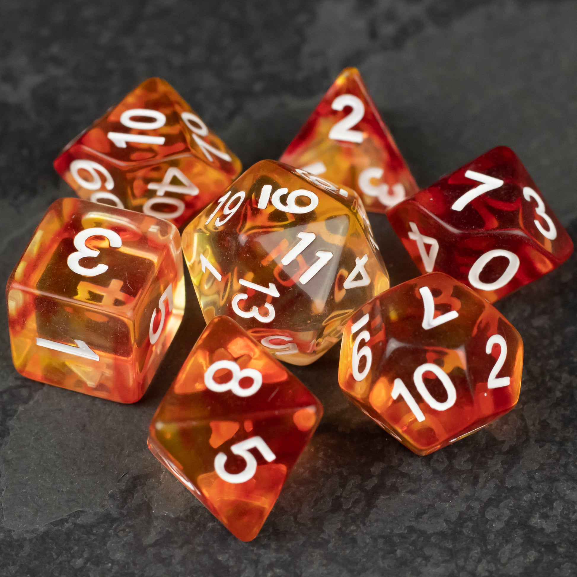 Magma Dice Set - Set of seven translucent orange and red tabletop RPG dice with white numbering on dark textured surface.