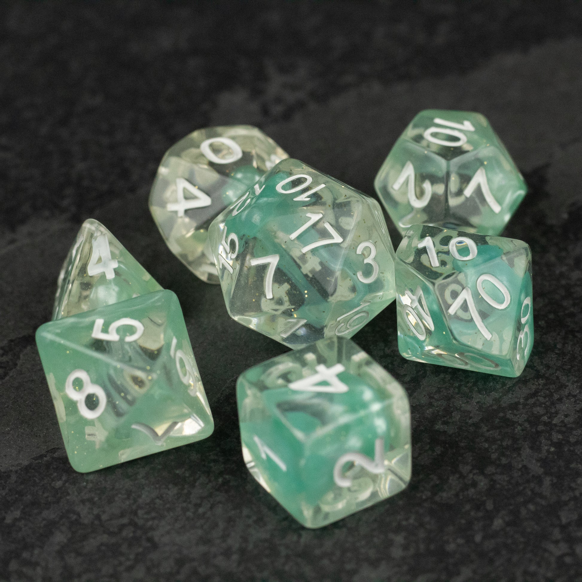 Cyan Lava Lamp Dice Set - Set of seven cyan translucent dice with white numbers, featuring various shapes including d20, d12, d10, d8, d6, and d4.