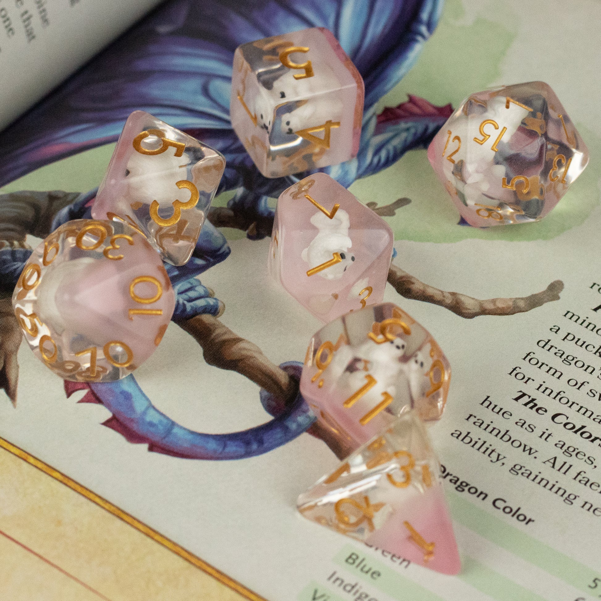 Polar Bear Dice Set - Translucent pink polyhedral dice set with gold numbers, featuring seven different shapes.