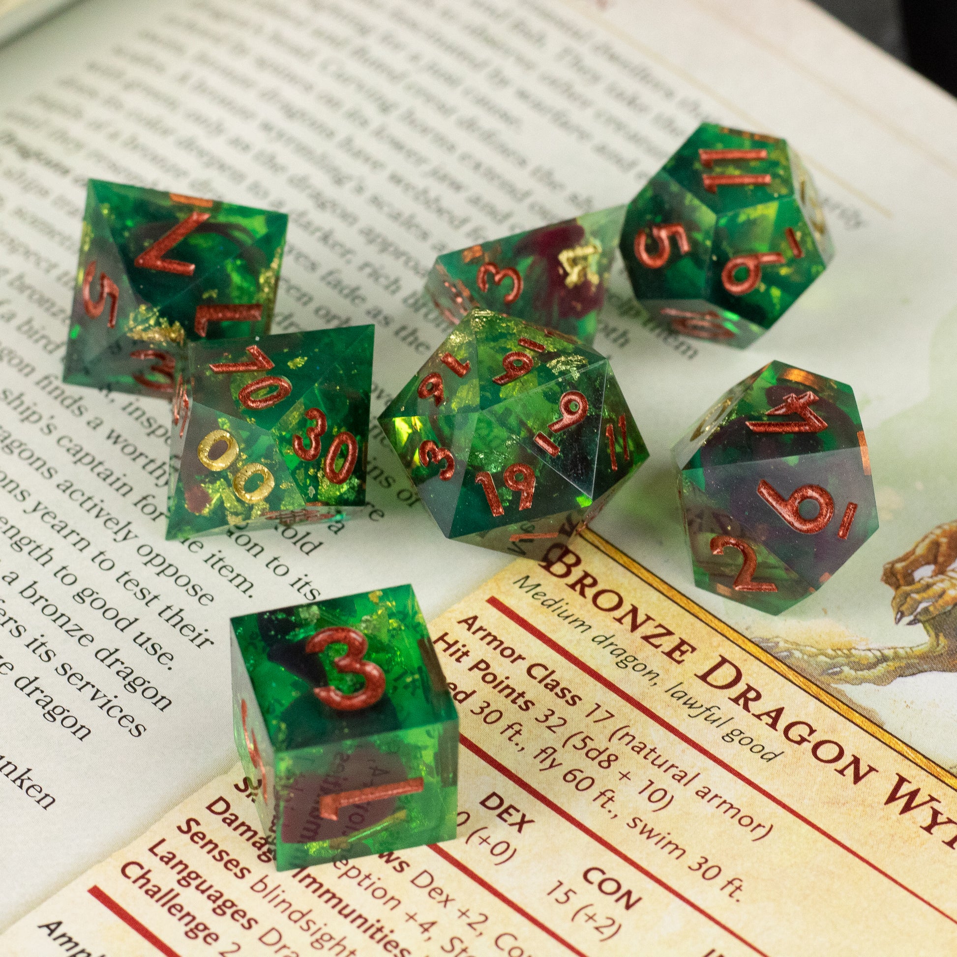 Primal Blood Dice Set - Seven green translucent sharp-edged dice with red and gold numbers on a book page background.