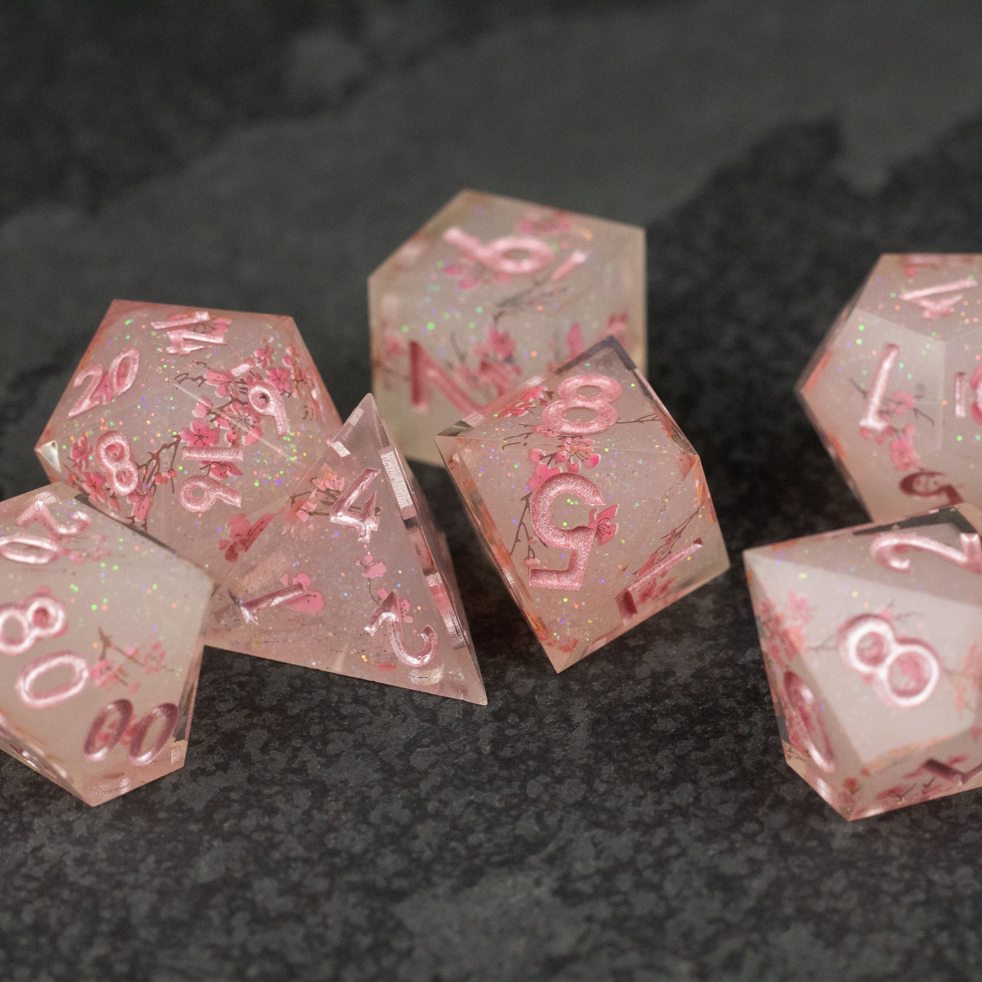 Pink Cherry Blossom Dice Set - Translucent pink multi-sided dice with sharp edges and metallic pink numbers, styled with cherry blossom details.