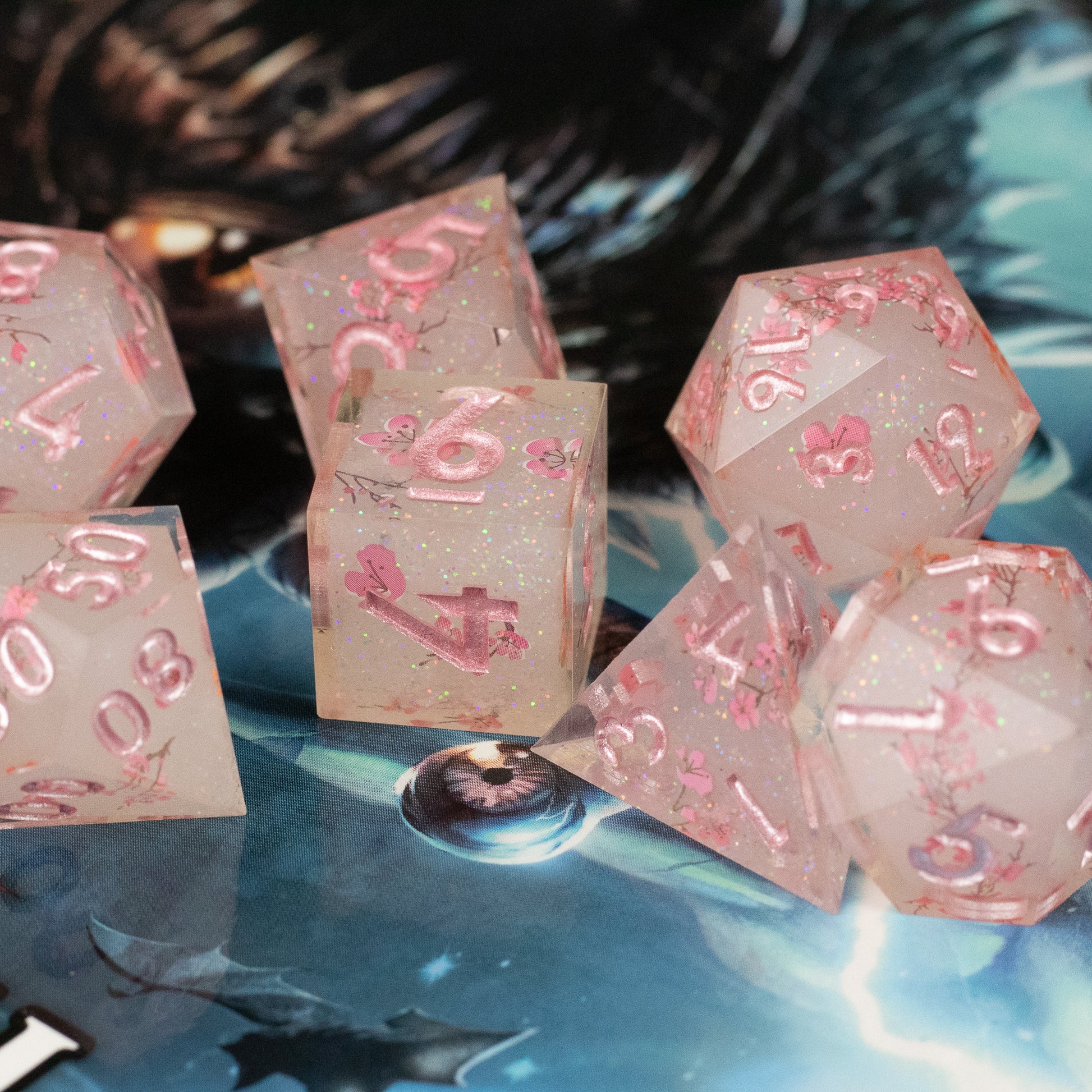 Pink Cherry Blossom Dice Set - Translucent pink sharp-edged polyhedral dice with cherry blossom inclusions and pink numbering.