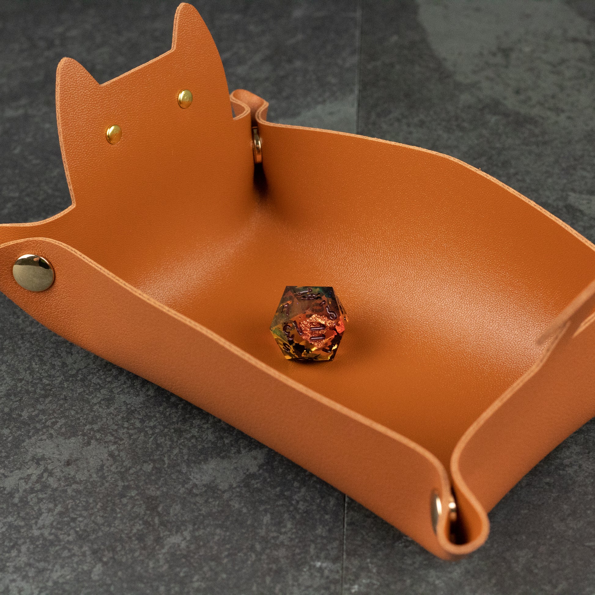 Cat Shaped Dice Tray - Brown leather dice tray shaped like a cat with brass snap buttons and a single colorful die inside.