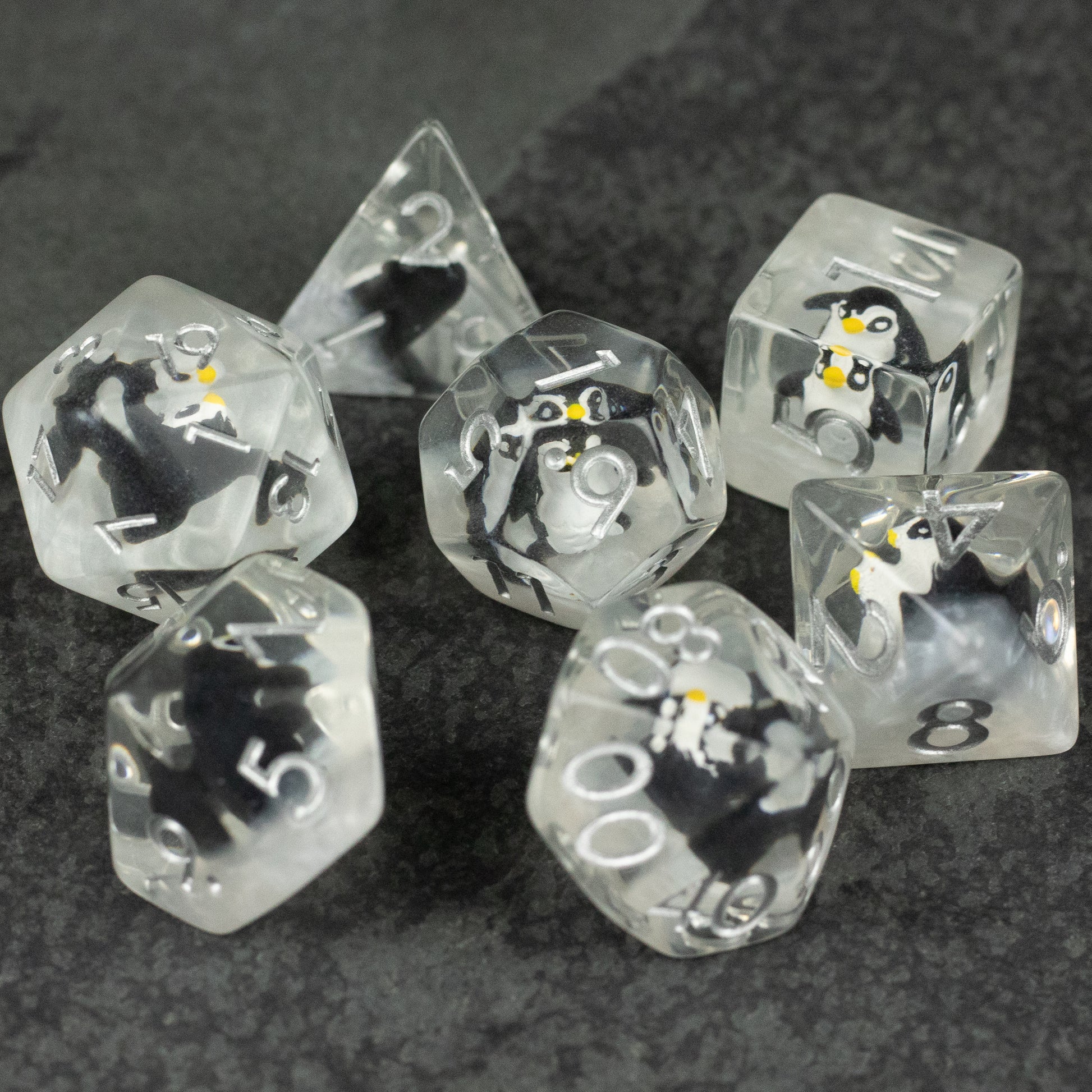 Penguin Dice Set - Clear acrylic polyhedral dice set featuring black and white penguin inclusions inside each die, with white numbering.