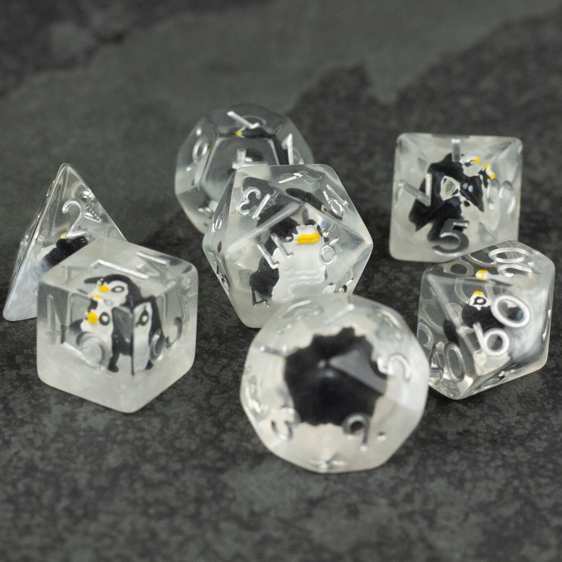 Penguin Dice Set - Clear polyhedral dice set with embedded miniature penguins, white and yellow details, and black numbering.