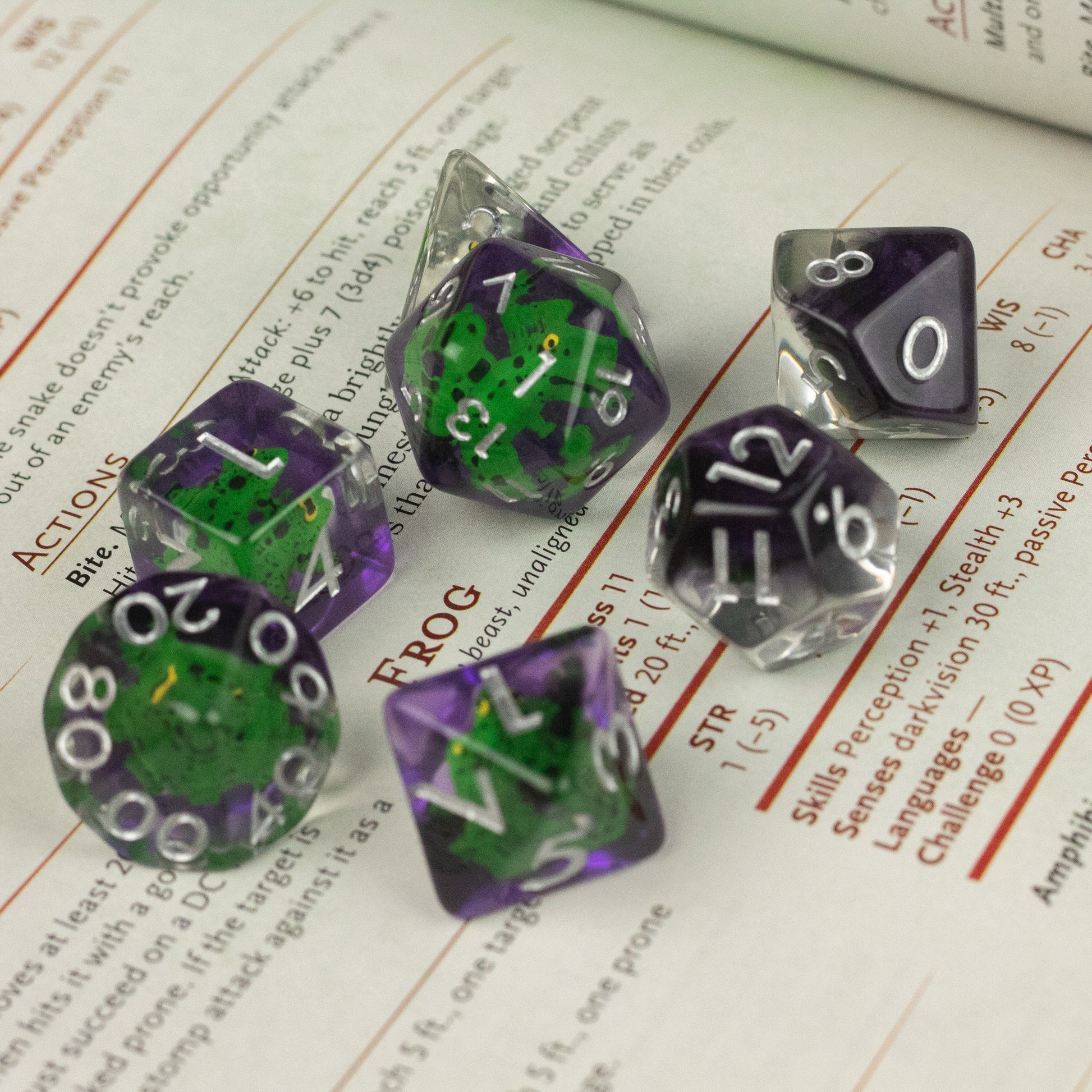 Green Frog Dice Set - Set of seven translucent green and purple polyhedral dice with white numbers, including d20, d12, d10, d8, d6, d4, and.