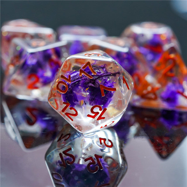 Purple Flower Dice Set - Type 2 - Transparent purple resin d20 dice with orange numbering and embedded purple flower inclusions.