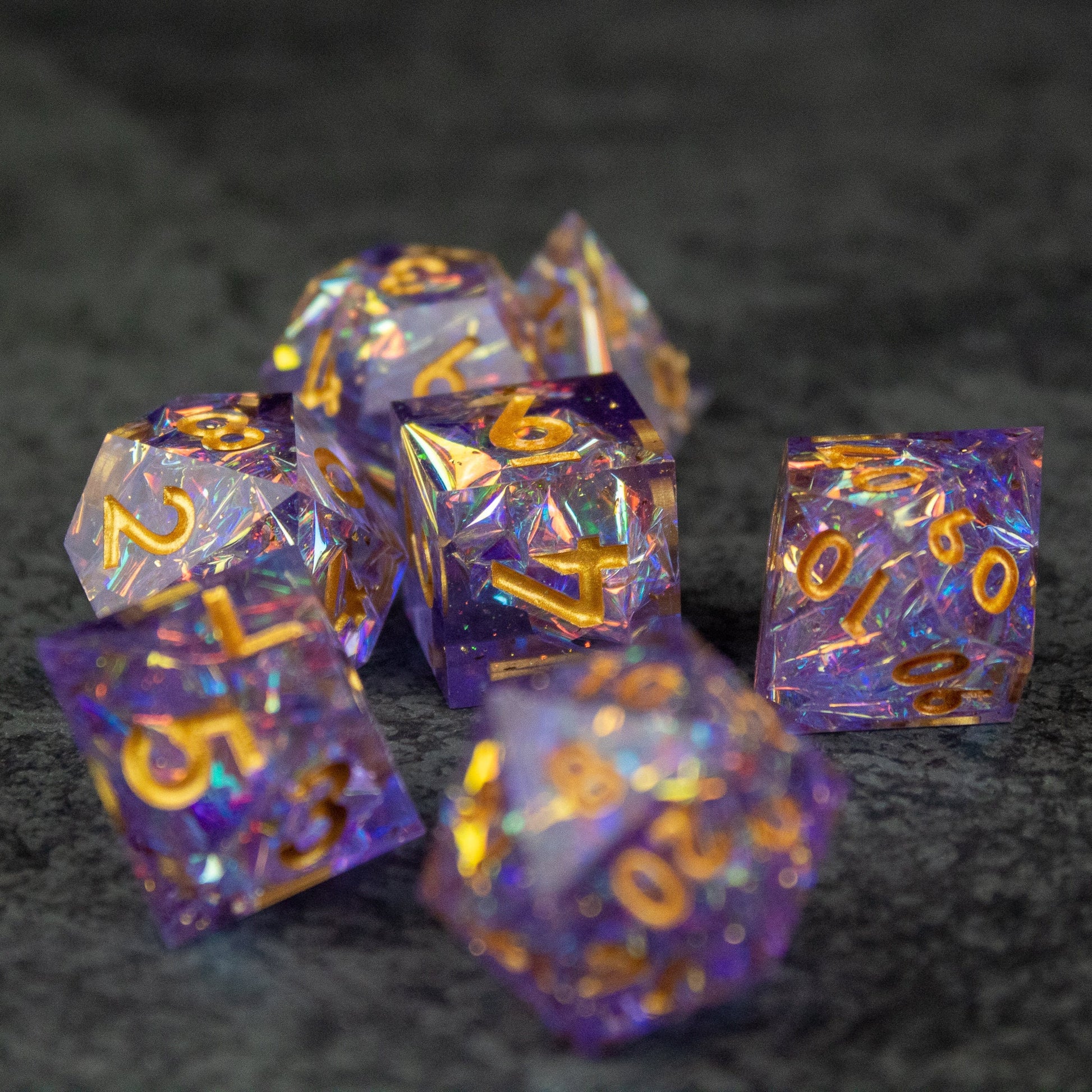 Feywild DnD Dice Set - Sharp Edge Dice for D&D - Set of seven sharp-edged translucent purple polyhedral dice with gold numbers and orange internal flakes for tabletop gaming.