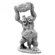 Bones Black: Two Headed Troll - Gray two-headed troll figurine with textured skin, holding a large rock above its heads, standing on an irregular base.